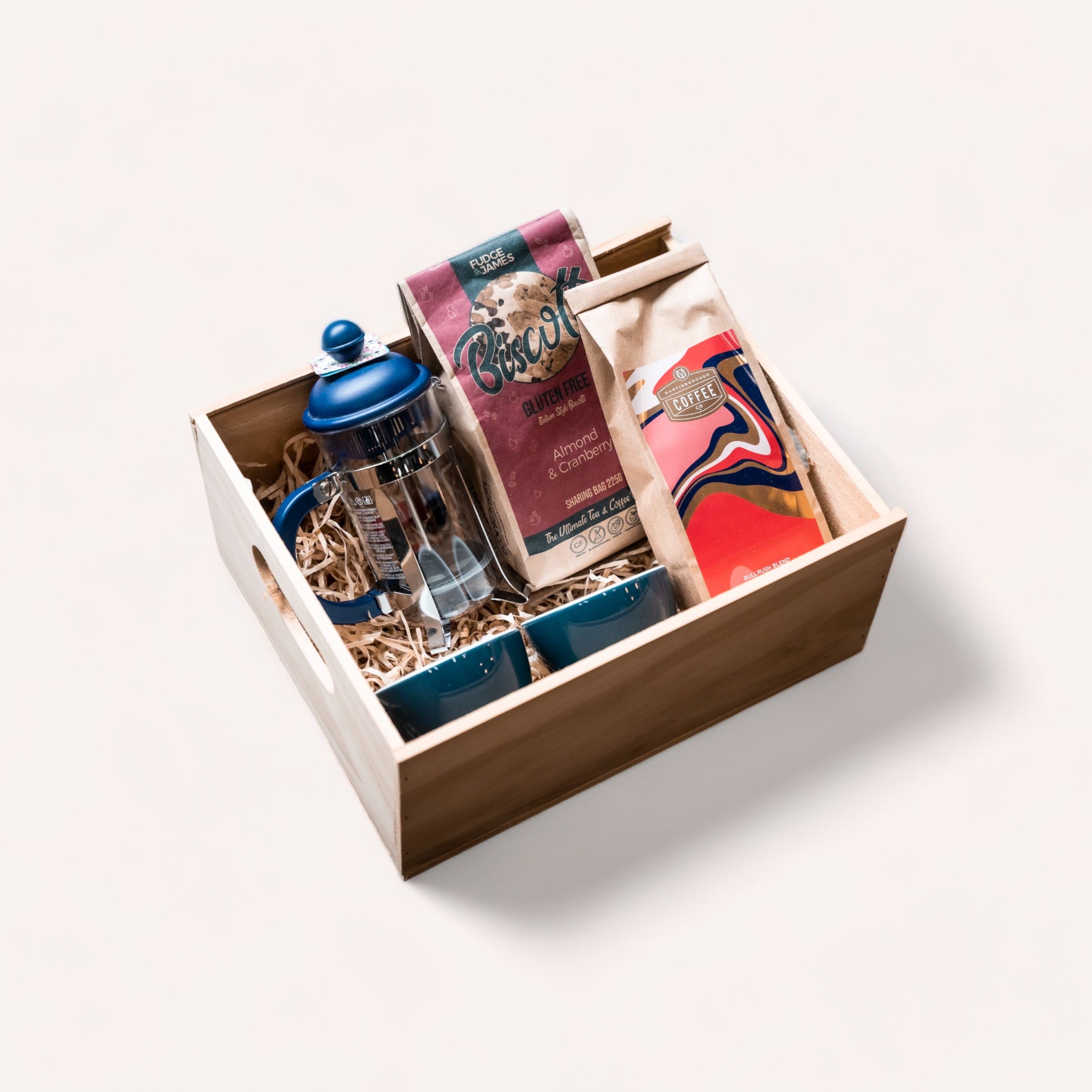 A cozy coffee-lover's gift set with an ACME Coffee Cups, gourmet Martinborough Coffee, and biscuits neatly arranged in a wooden box with compartments from giftbox co.