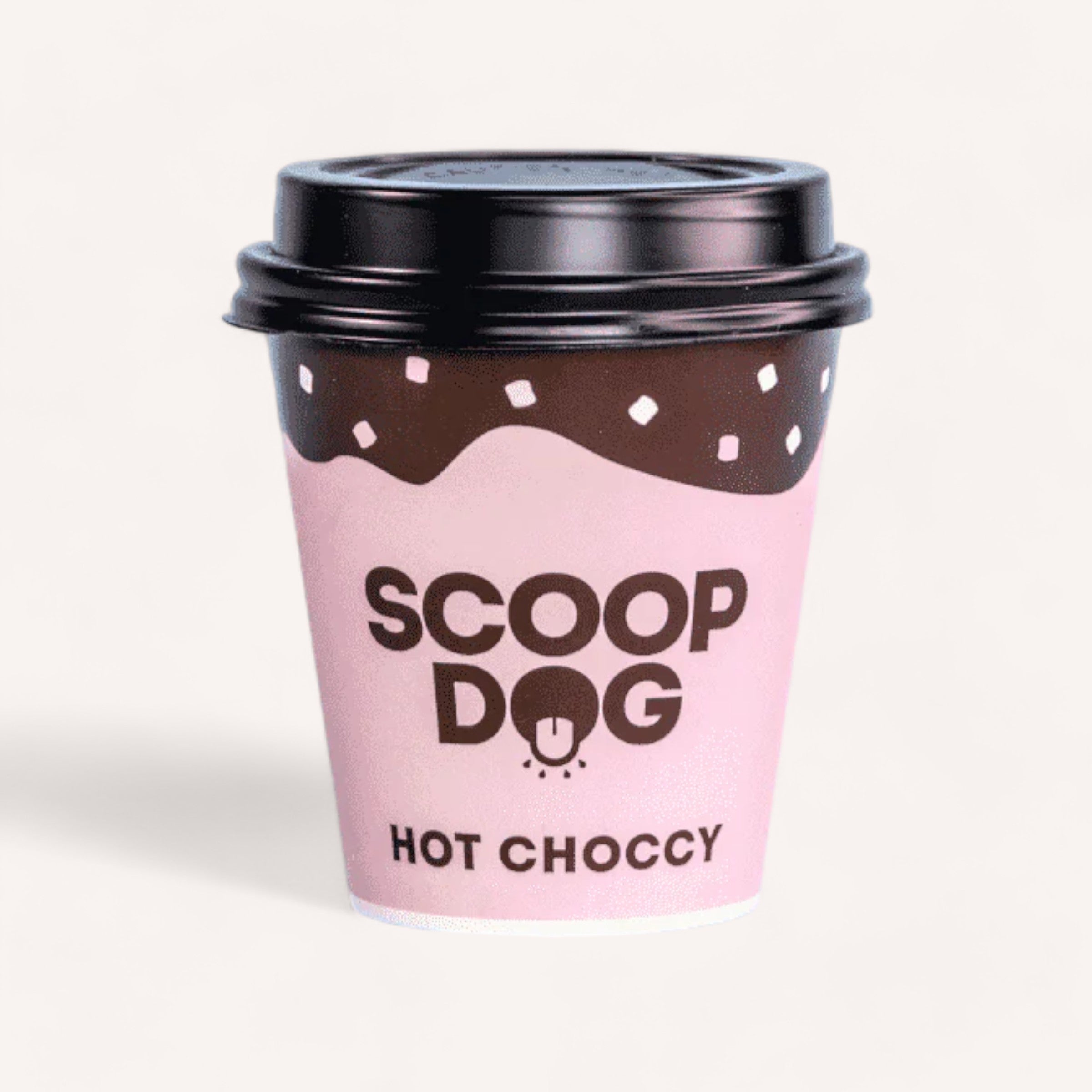 A cute illustrated disposable coffee cup with a pink design, featuring the words "Hot Choccy Dog Drink by Scoop Dog," "hot choccy," and "PAWS" on it, likely containing hot choccy mix.