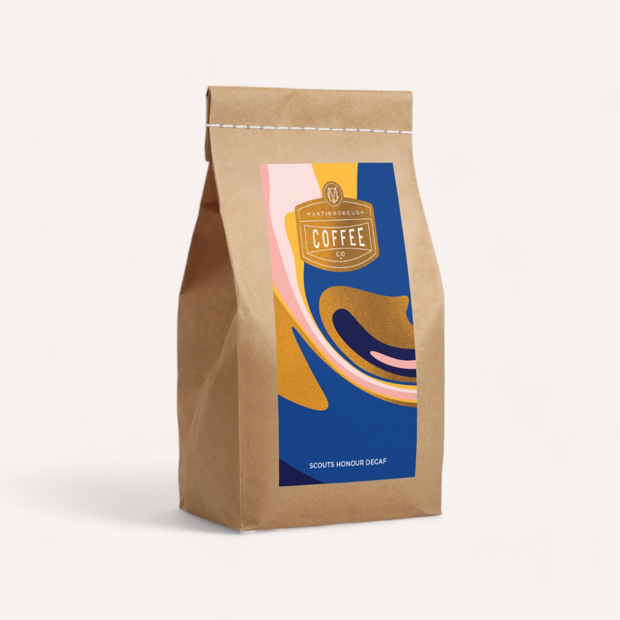 A neatly sealed brown craft paper coffee bag with a vibrant, modern label design stands against a white background, labeled as Scouts Honour Decaf Coffee by Martinborough Coffee Company for a medium-bodied coffee.