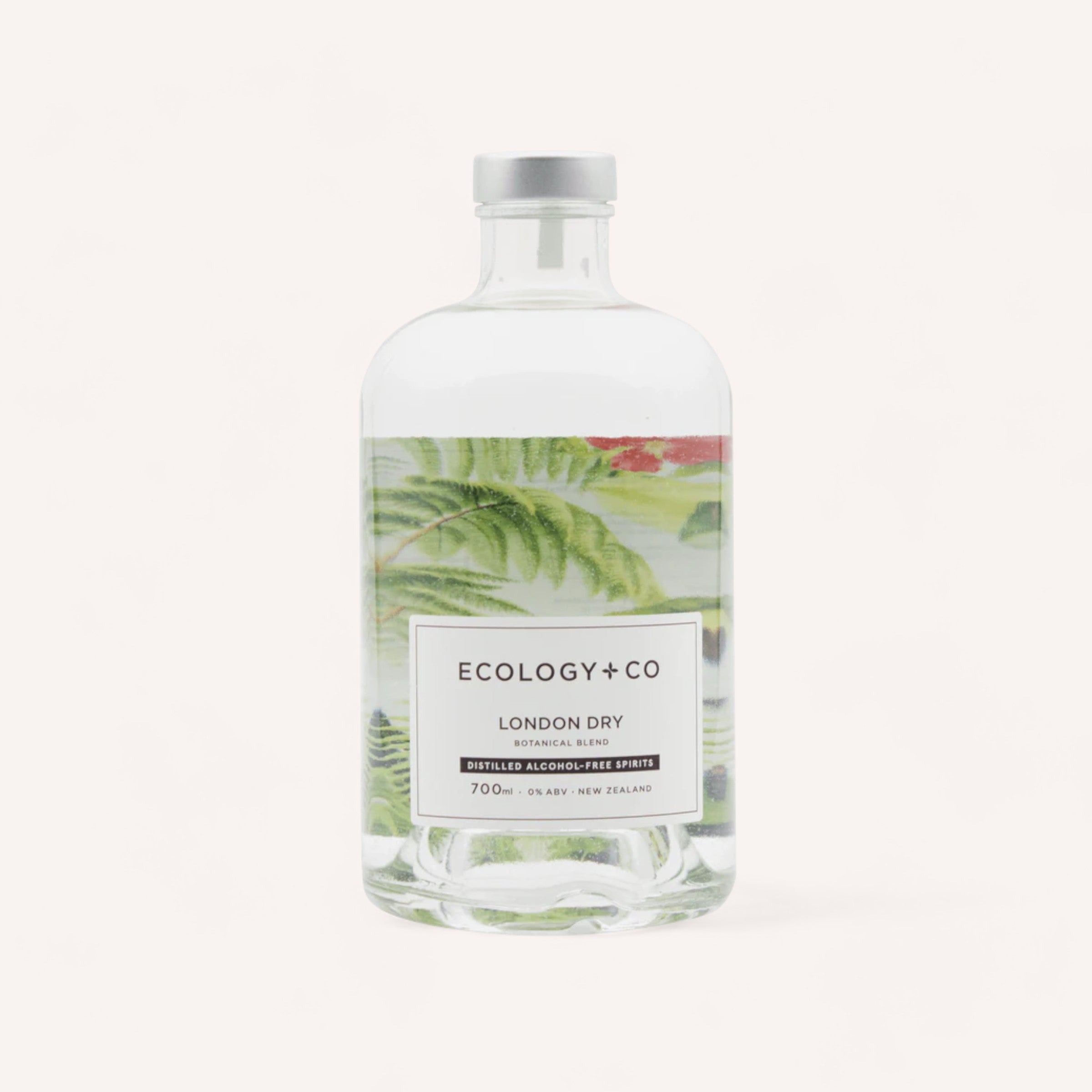 A clear glass bottle of Ecology & Co London Dry Zero Alcohol Gin against a white background, with a hint of green botanical artwork visible behind the liquid.