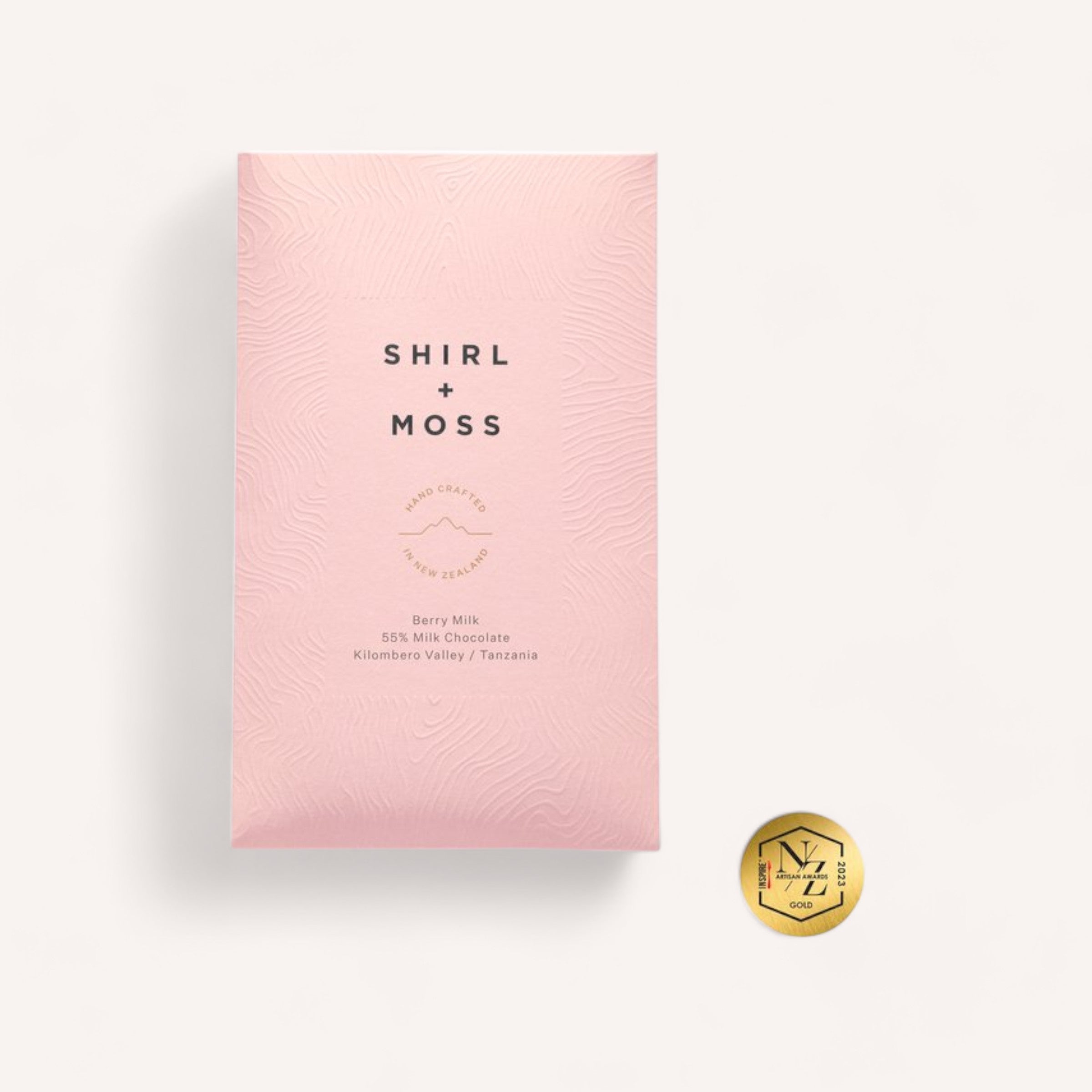 A single Berry Milk Chocolate bar wrapper with elegant text overlay, accompanied by a gold embossed seal on a clean, white background by Shirl & Moss.