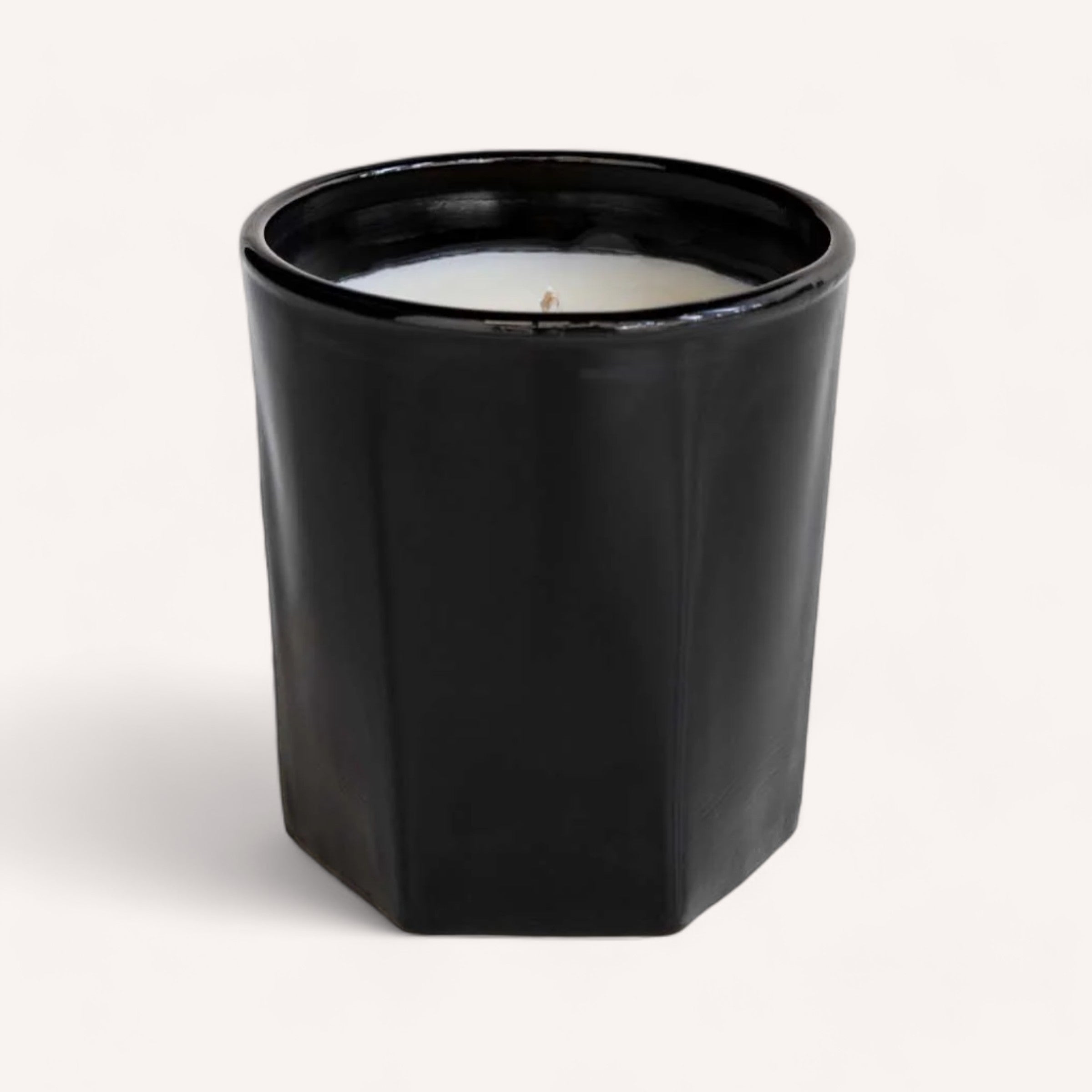 A single-wick, handcrafted Remana & Orange Blossom candle by Real World within a sleek black cylindrical container against a clean white background.