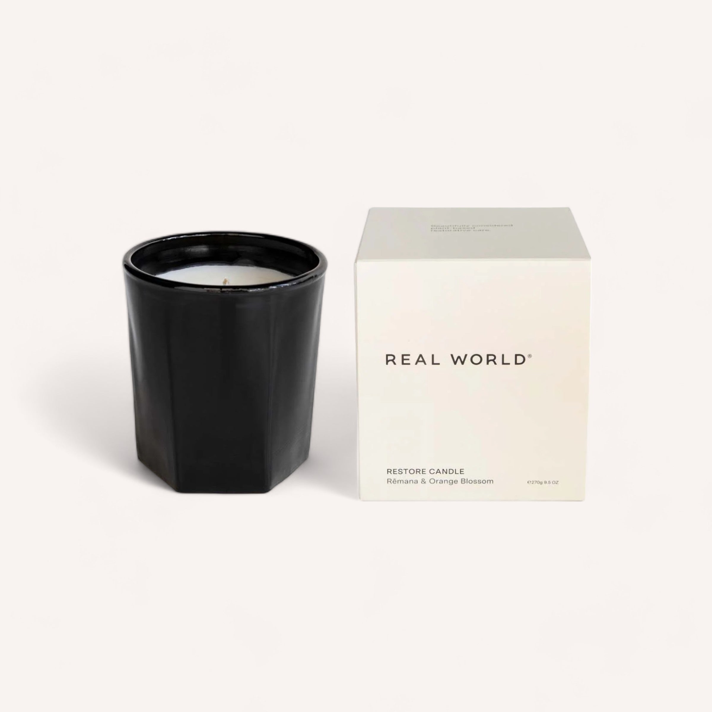 Elegant black handcrafted Remana & Orange Blossom Candle next to its minimalist packaging with the scent description "restore candle rosemary & orange blossom" from the brand Real World.