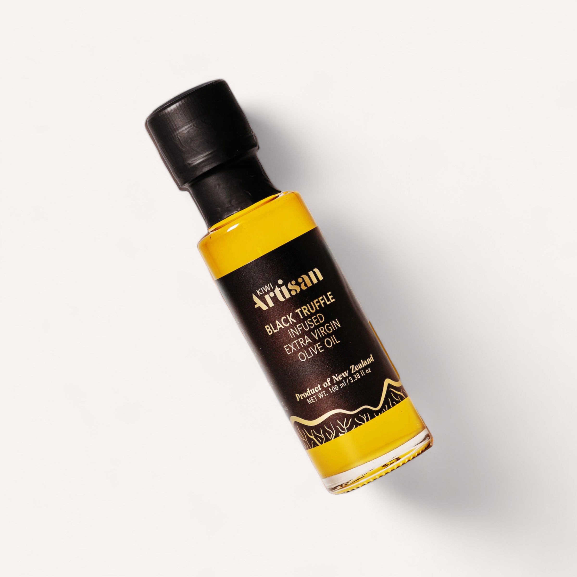 A small bottle of Black Truffle Extra Virgin Olive Oil by Kiwi Artisan, crafted using New Zealand truffles, showcases a black label adorned with gold and white text. Positioned against a plain white background, it emphasizes the rich golden hue of the premium oil inside.