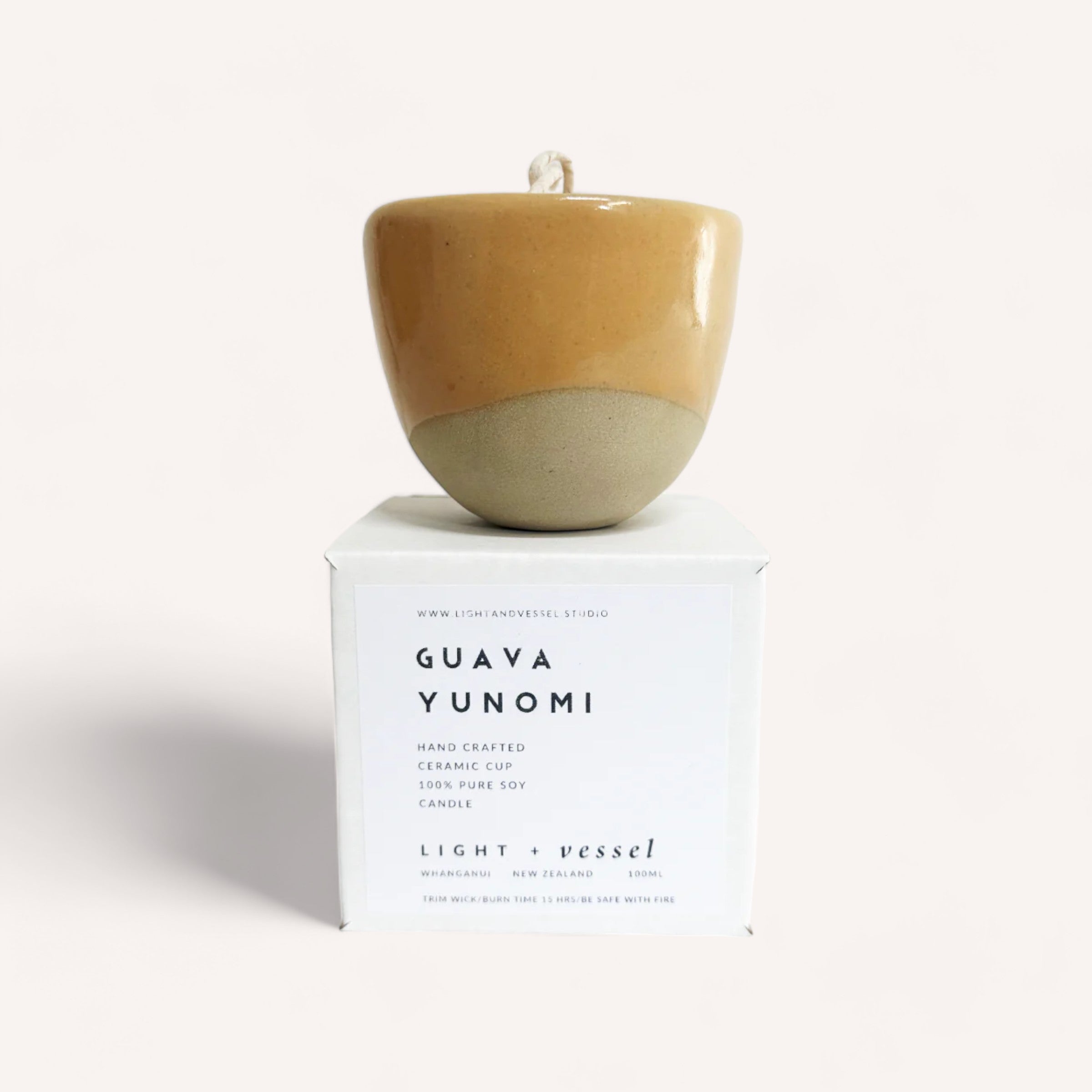 A handcrafted ceramic cup labeled guava yunomi by Light + Vessel, presented on a clean white background, accompanied by a Guava Candle by Light + Vessel infused with natural fragrance oils.