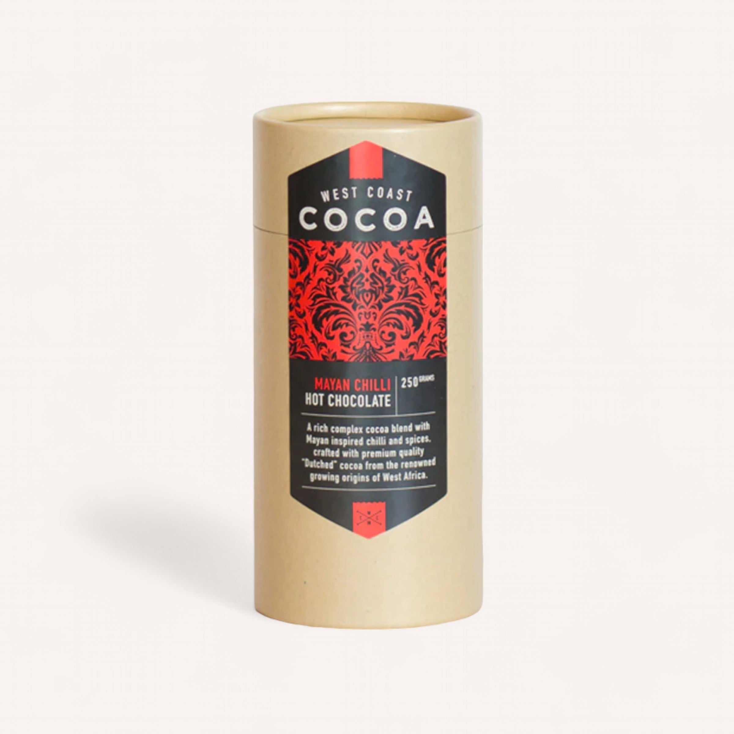 A beige cylindrical package branded as "West Coast Cocoa" from New Zealand features a decorative red design. The label states "Hot Chocolate by West Coast Cocoa," offering premium quality hot drinking chocolate infused with Mayan spices, made from West African cocoa. The container holds 250 grams.