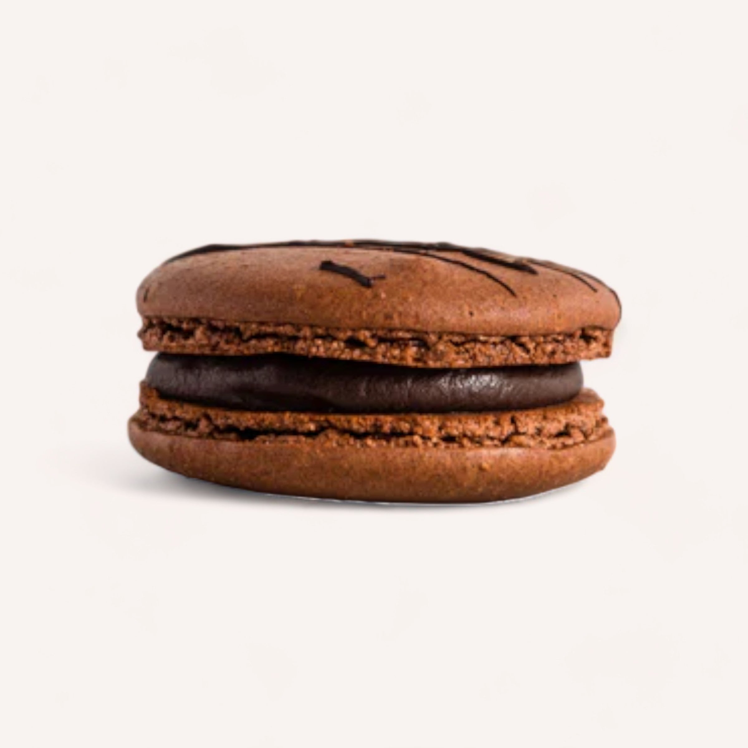 A handcrafted chocolate macaron by J'aime les Macarons features a smooth and glossy chocolate filling. The rich brown shells offer a slightly textured surface, adorned with dark chocolate drizzle. Made from the finest ingredients in Christchurch, this macaron by J'aime les Macarons stands out against a plain white background, emphasizing its intricate details and vibrant color.