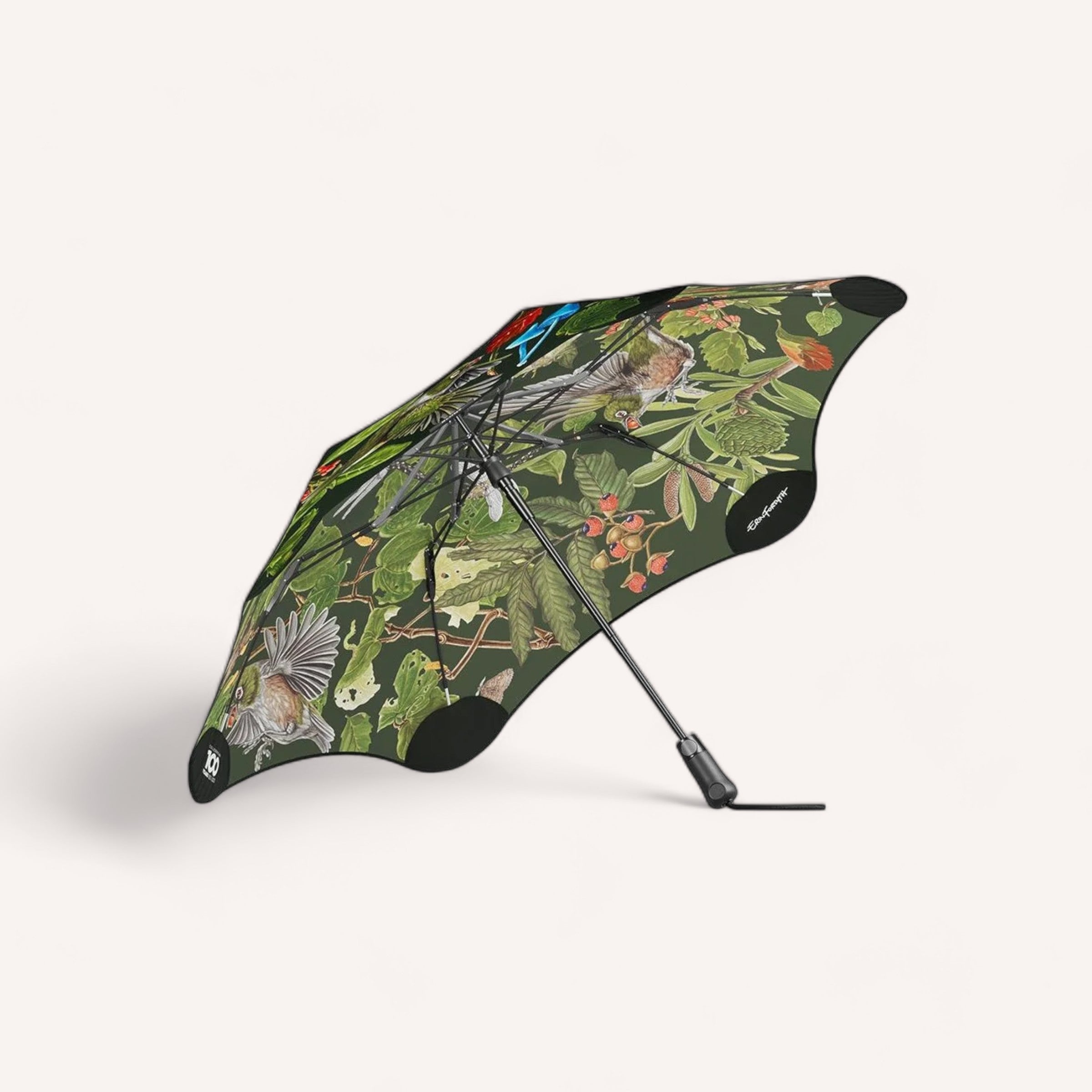 An open compact BLUNT Metro umbrella featuring the Blunt Metro Umbrella Forest & Bird - Limited Edition design stands against a white background, showcasing a mixture of flora and fauna in a colorful illustration.
