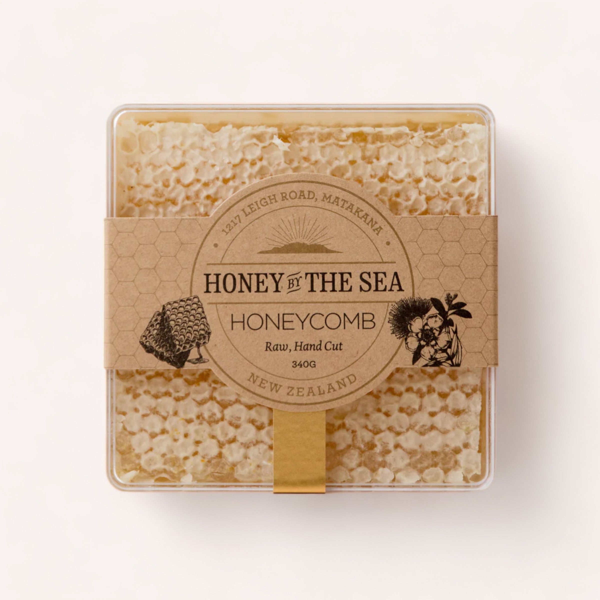A package of raw, hand-cut Honeycomb by Honey by the Sea from New Zealand honey, with the product neatly presented in a clear box, showcasing the natural texture of the honeycomb against a neutral background.
