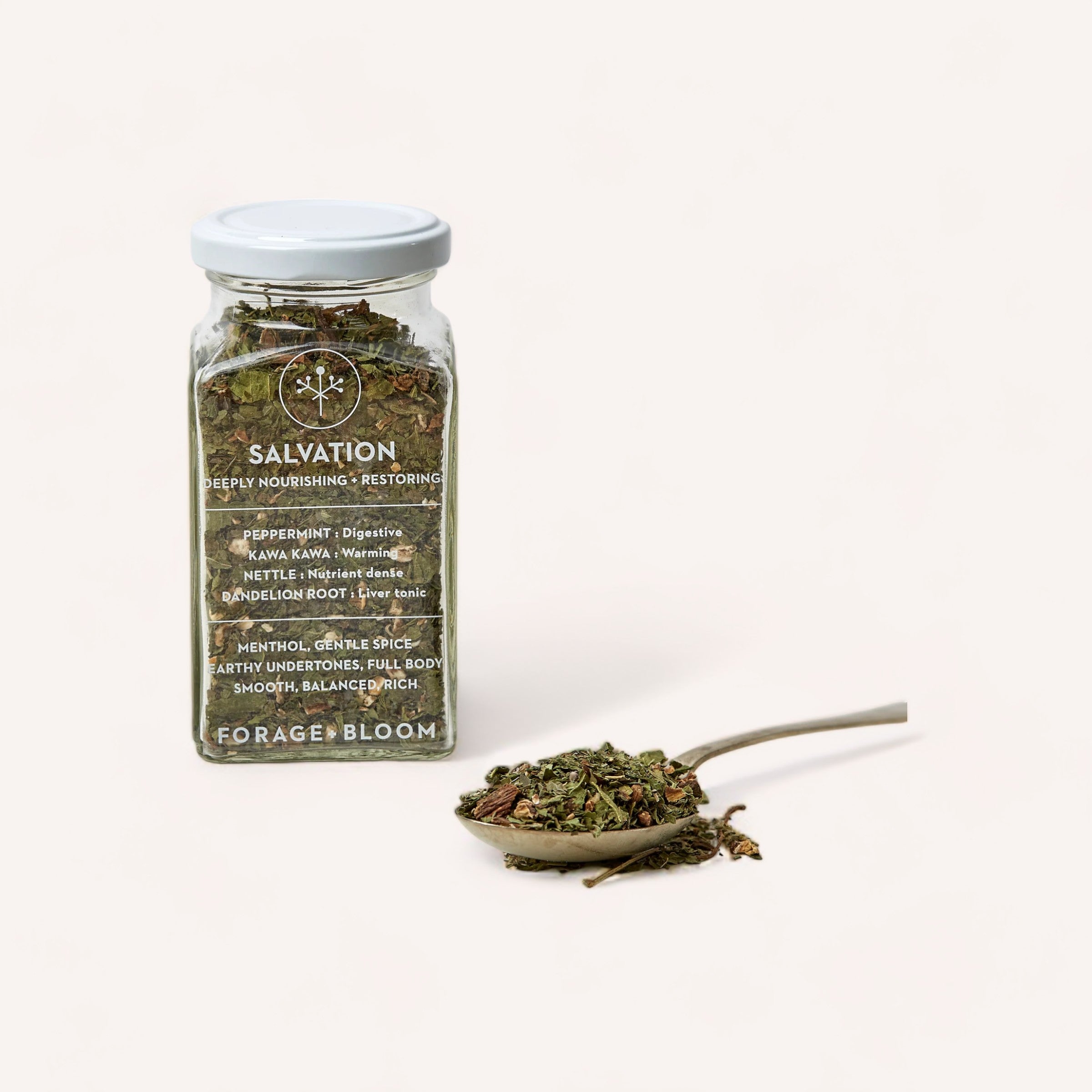 A jar of 'Salvation Tea' by Forage + Bloom digestive herbal tea with a spoonful of loose leaf blend beside it on a white background.