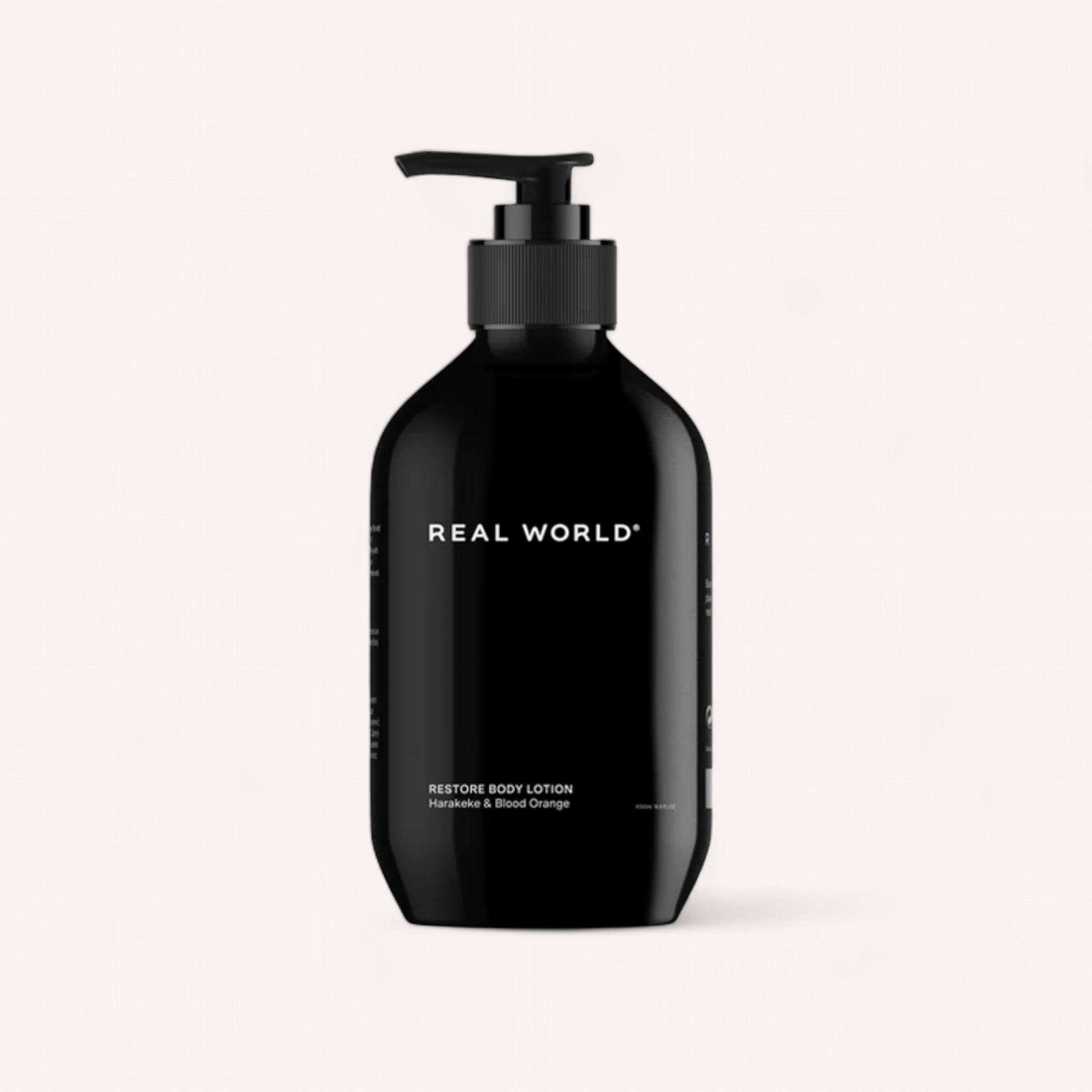 A sleek, black pump bottle of Real World Body Lotion by Real World. The minimalistic design features the brand name in white text. Below, it reads "Body Lotion" with key ingredients like "Hazelnuts, Harakeke & Blood Orange," also displayed in white text. The background is a light beige.