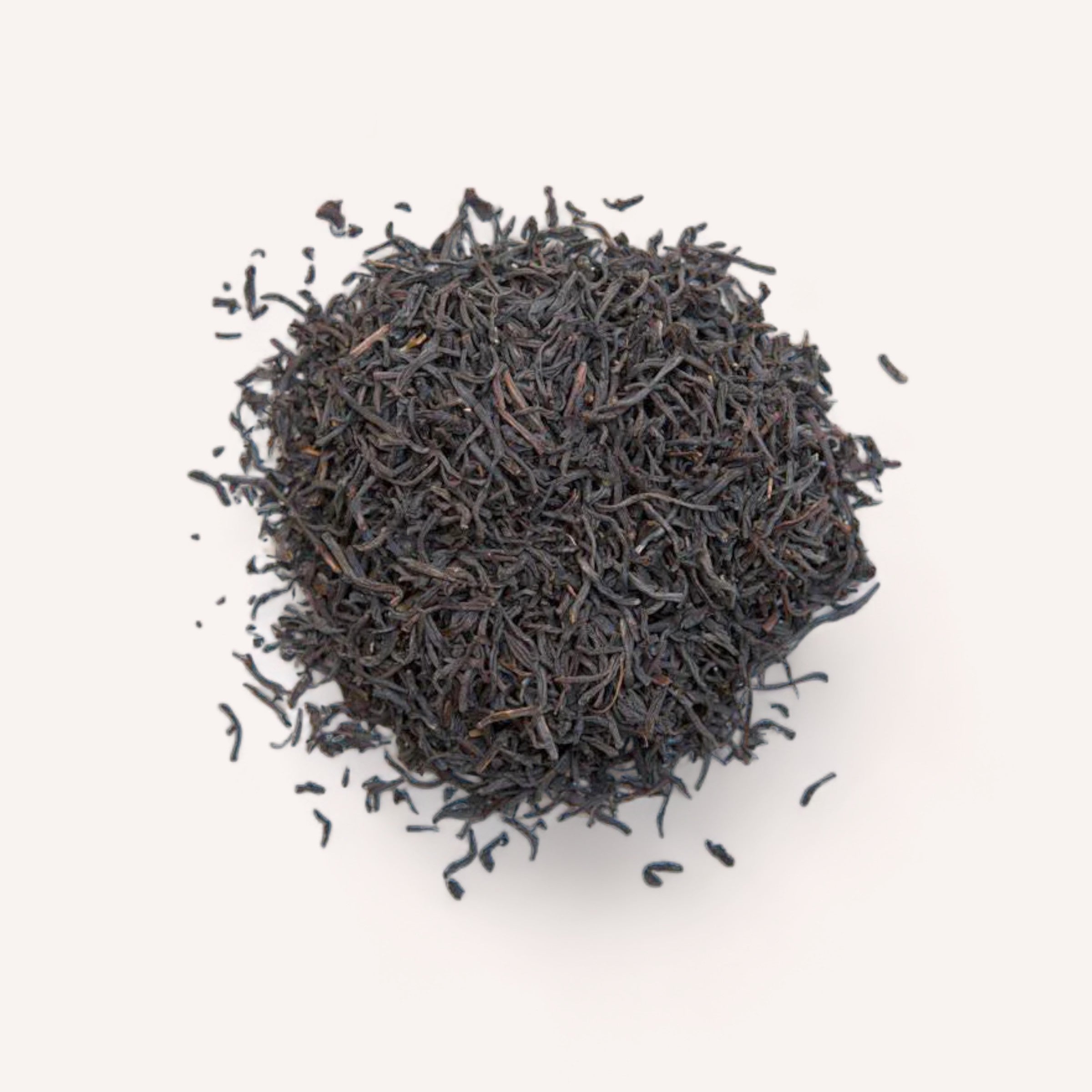 A mound of loose English Breakfast Tea by Forage + Bloom black tea leaves, rich in antioxidants, isolated on a white background.