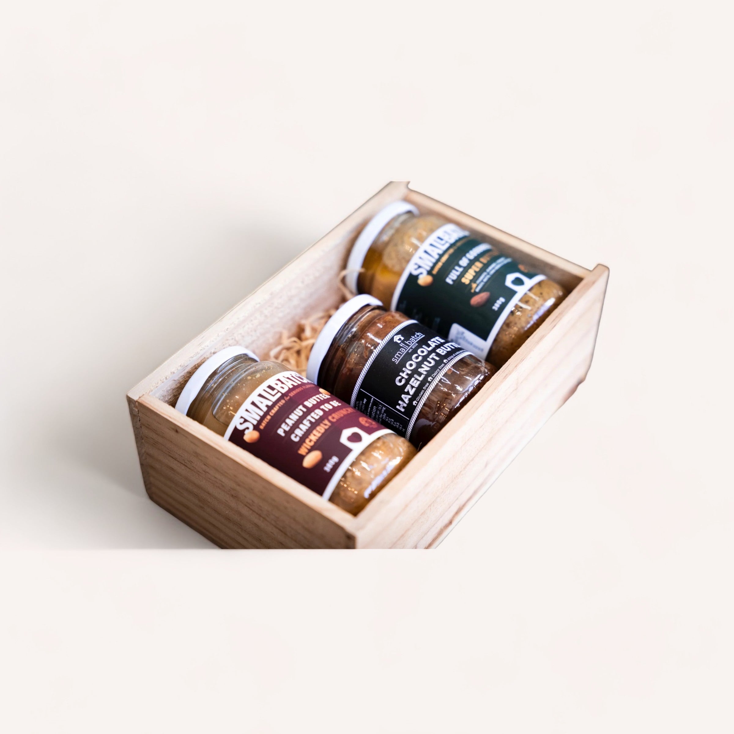 A wooden gift box containing a selection of Spread the Love gourmet small-batch spreads, including Spread the Love peanut butter and chocolate hazelnut butter.