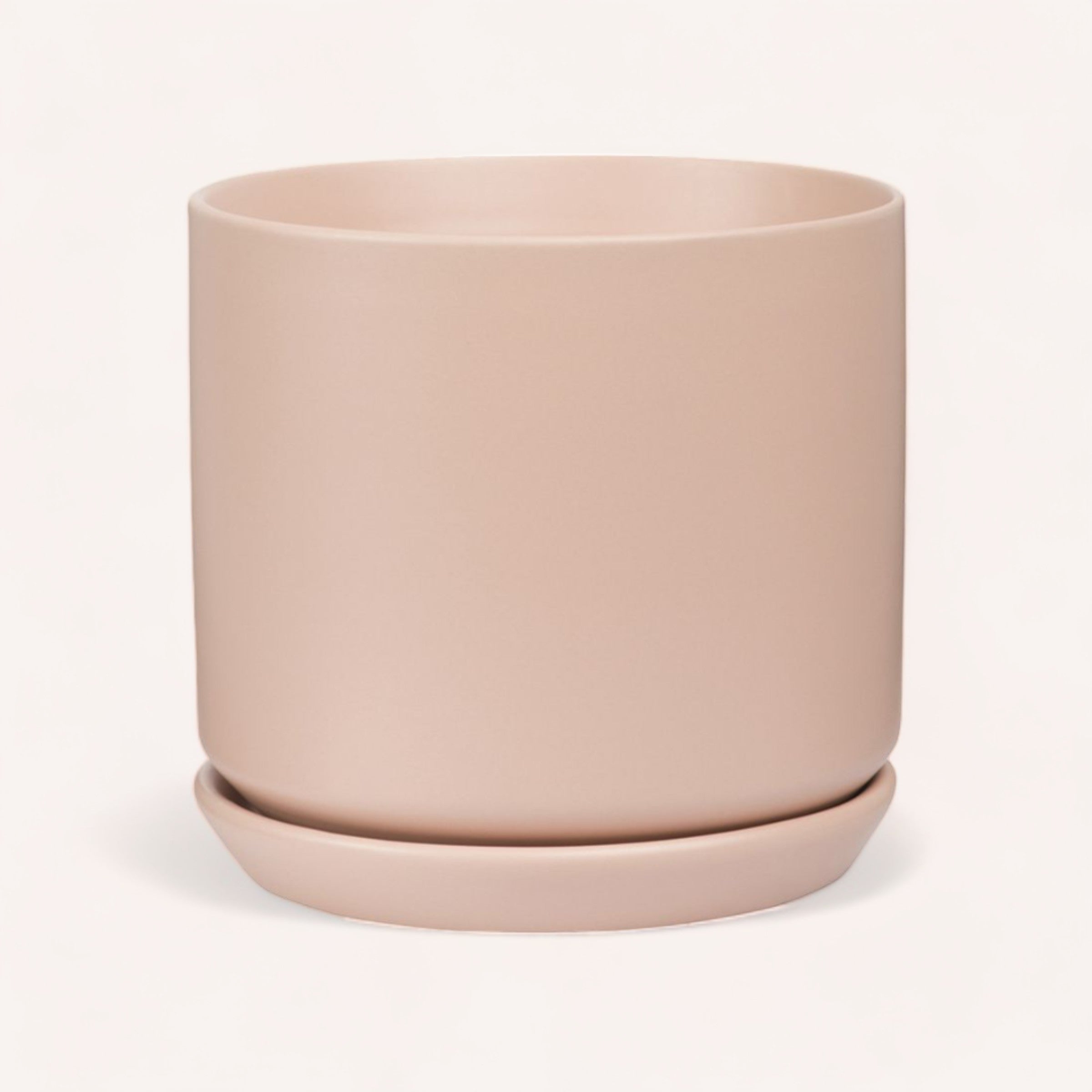 A simple, elegant peach-colored Oslo Planter by PottedNZ with a matching saucer, isolated on a clean, white background.