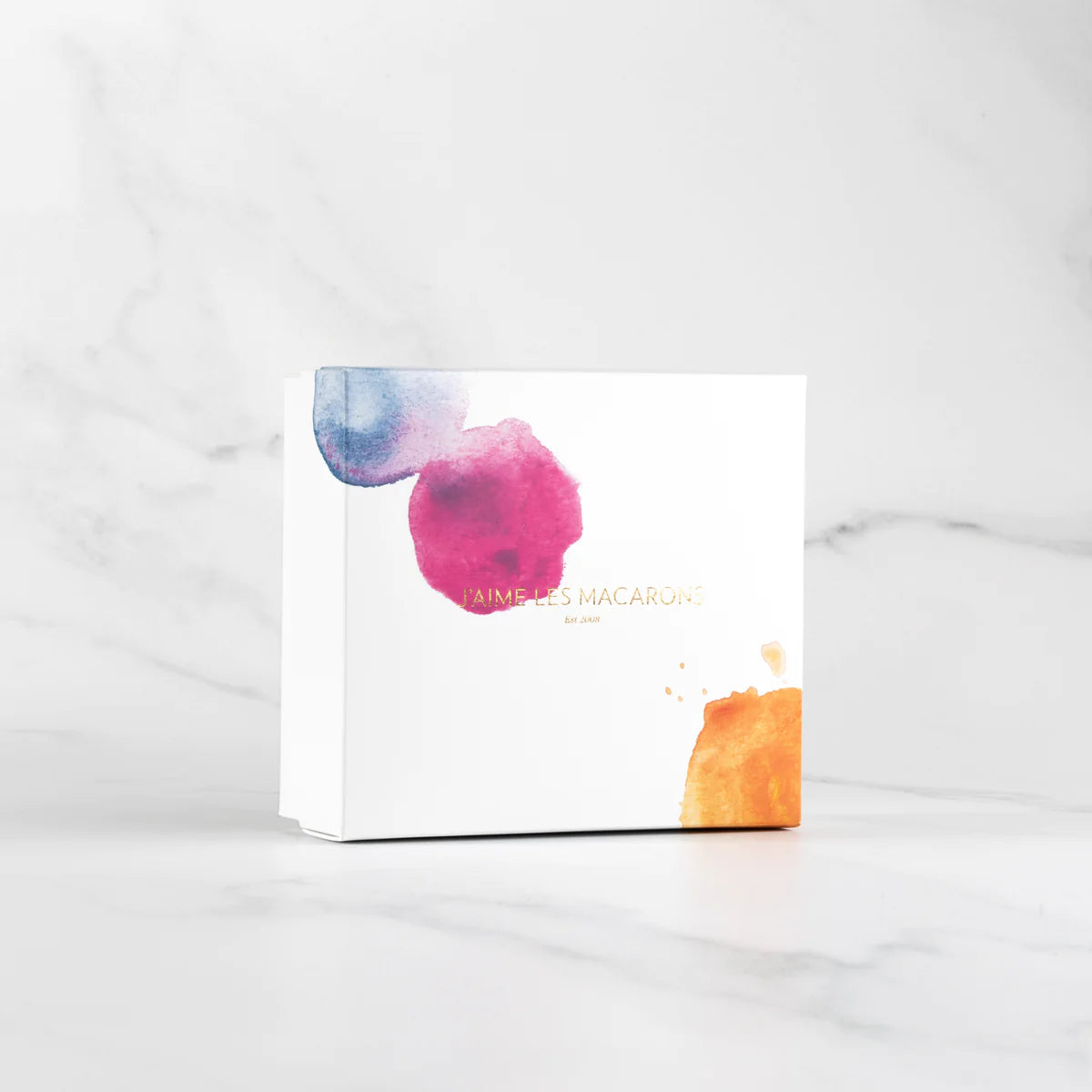 A minimalist and elegant handmade Box of 12 Macarons by J'aime les Macarons packaging design with watercolor accents on a marble background, crafted in Christchurch, New Zealand.
