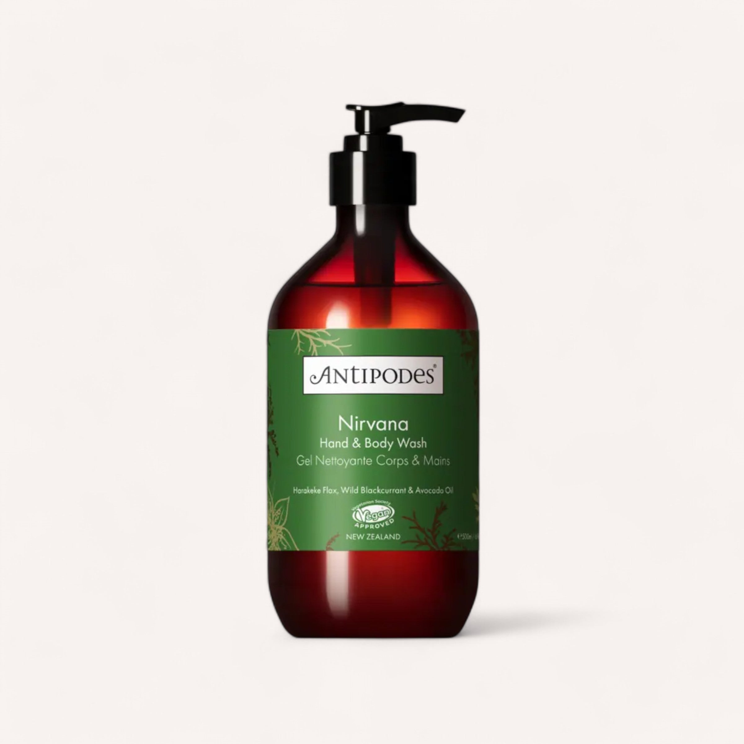 The Nirvana Hand & Body Wash by Antipodes is housed in a dark amber bottle with a black pump dispenser. The green label features white and gold text, highlighting ingredients like Harakeke Flax, Wild Blackcurrant, and Avocado Oil. The brand logo is prominently displayed at the top.