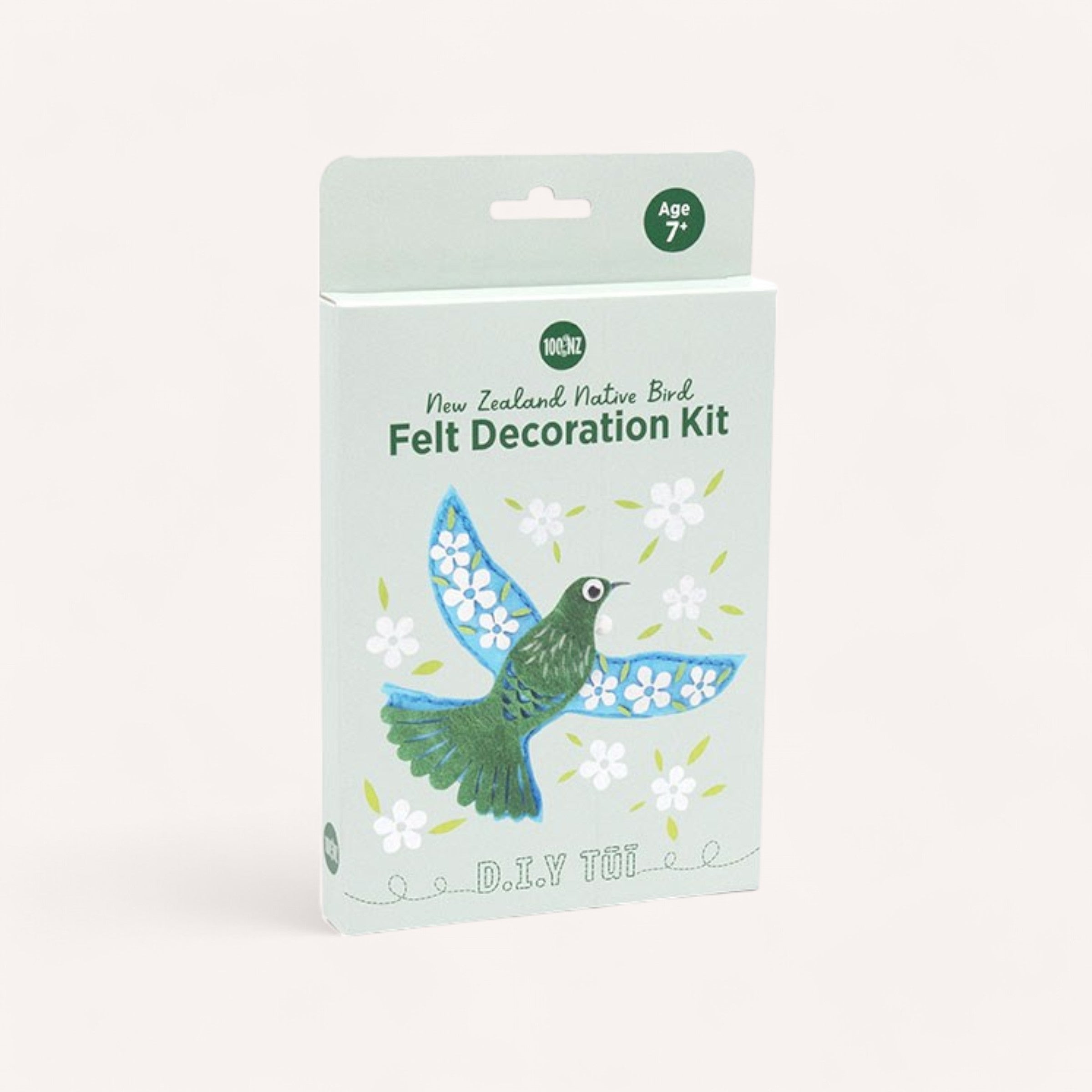 A pastel green box contains the "Tui Felt Decoration Kit" from 100% NZ, offering a unique crafting experience with a blue and green tui bird design adorned with white flowers. Labeled as "D.I.Y TUI," it promises creative fun for ages 7 and up.