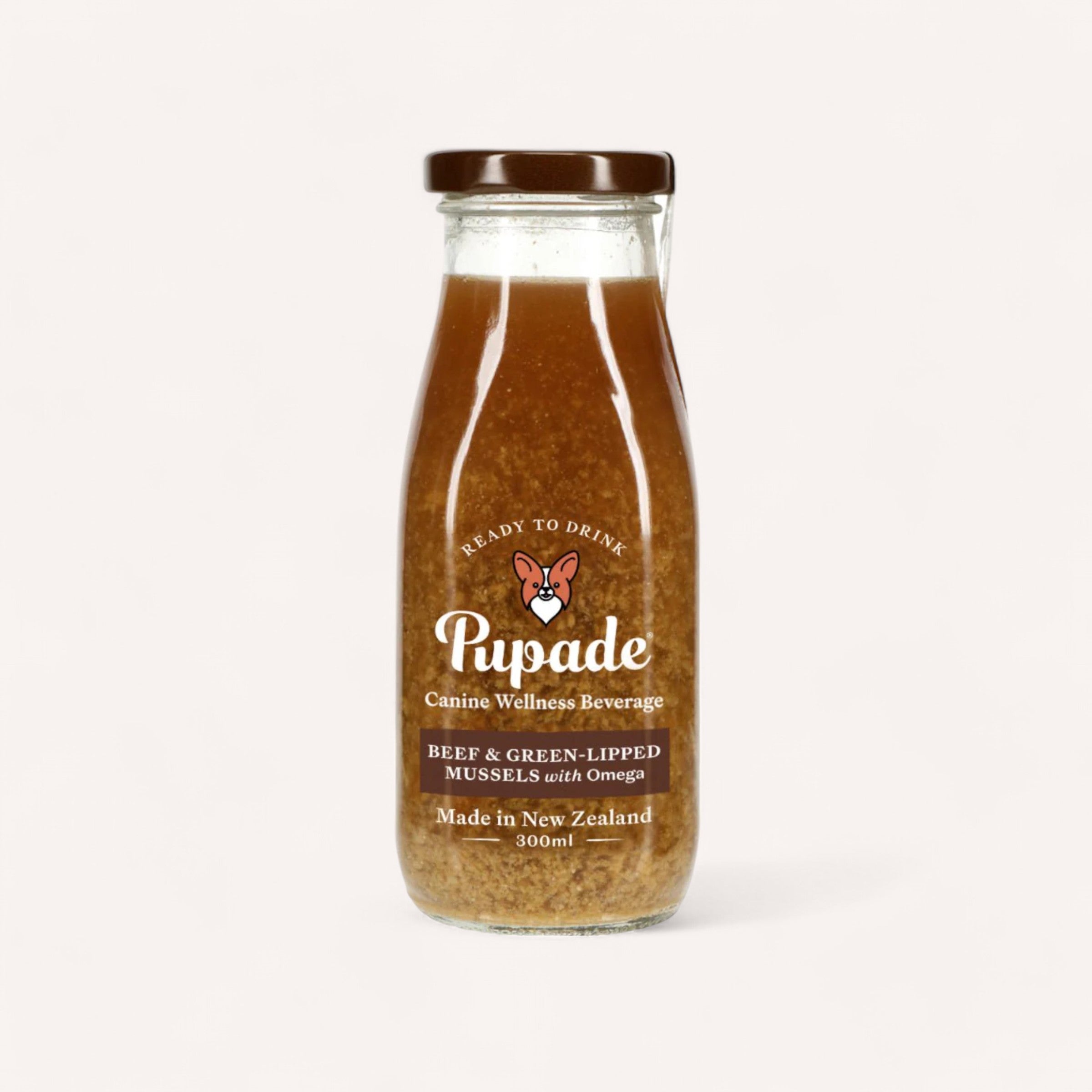 The Pupade Dog Beverage, a nutrient-rich wellness drink for dogs, boasts a brown label adorned with white text and a dog icon. This 300ml beverage is crafted in New Zealand and features flavors of beef and green-lipped mussels. Enhanced with Omega and made from natural ingredients, it comes with a dark brown cap.