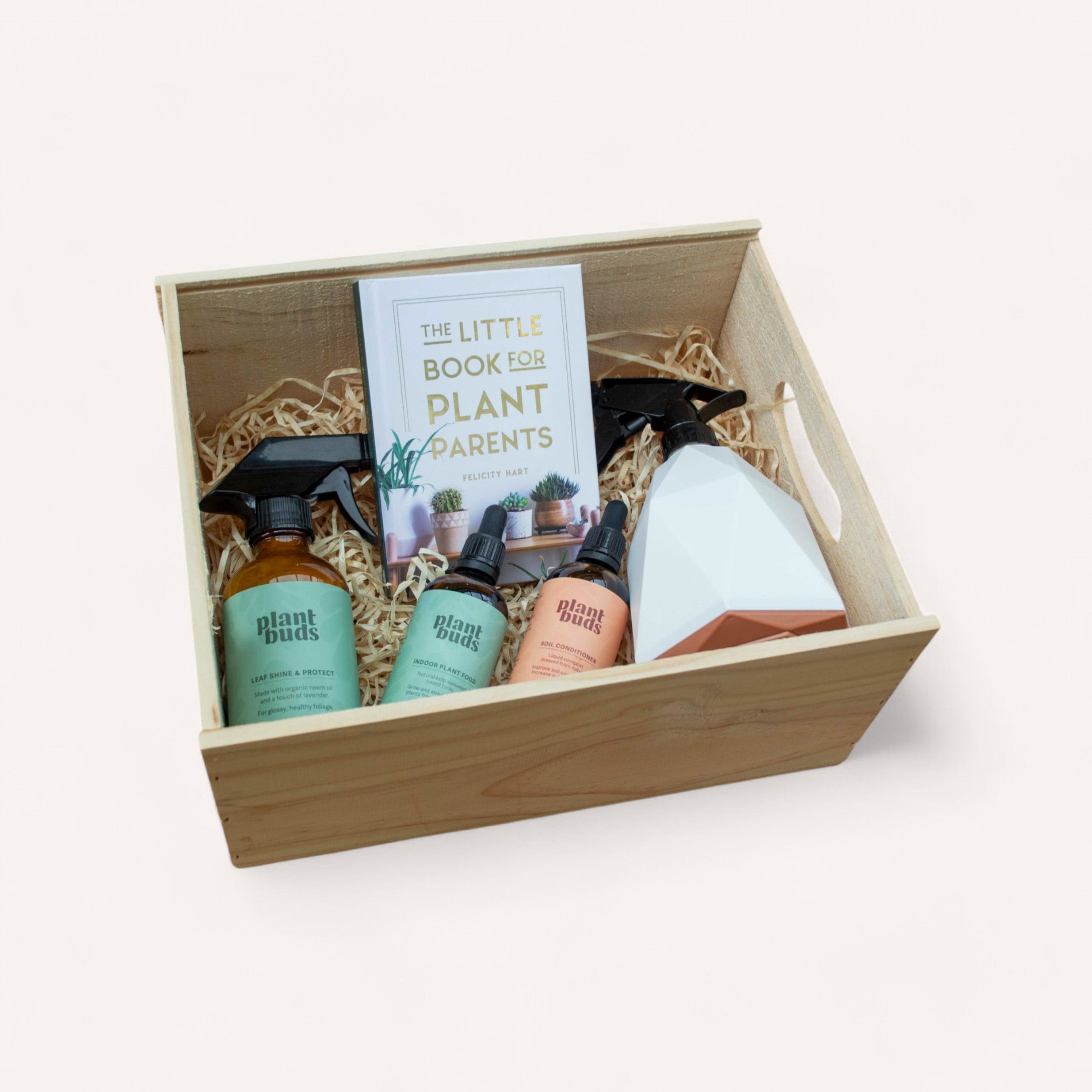 The delightful "Ready, Set, Grow" gift by giftbox co. features a wooden box containing "The Little Book for Plant Parents," a set of three "plant buds" spray bottles, and a stylish geometric white and terracotta pot. Everything is carefully arranged in straw-like packing material, making it an ideal choice for all your indoor plant care essentials.