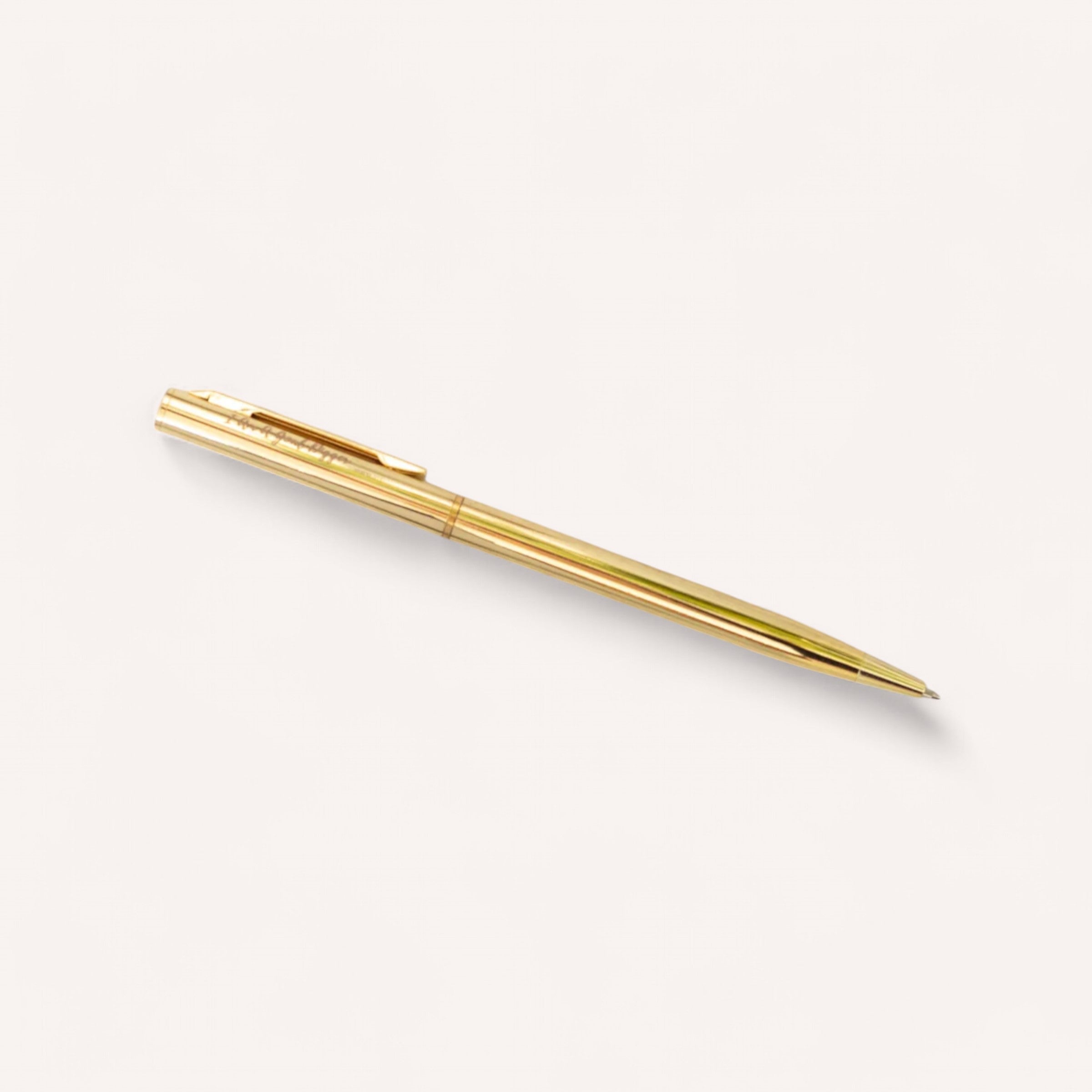 The "Mindful Moments" gold ballpoint pen by giftbox co. rests diagonally against a plain white background, ideal for noting down your thoughts in a reflection journal. Its sleek and elegant design, featuring a visible clip, makes it a perfect addition to any luxurious self-care gift box.