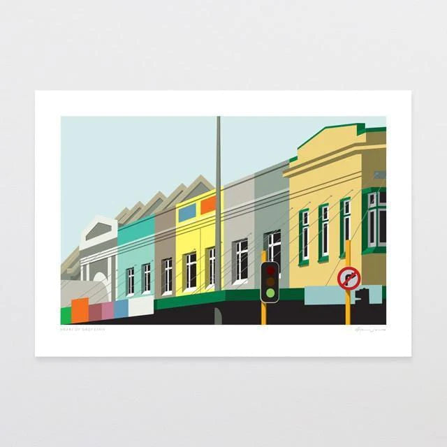 The artwork "Heart of Grey Lynn" by Glenn Jones showcases a minimalist illustration featuring a row of colorful buildings in shades of yellow, gray, and turquoise in a downtown area. In the foreground, there is a traffic light with red and green signals and a 'No Right Turn' sign. The scene is set against the backdrop of a light blue sky.