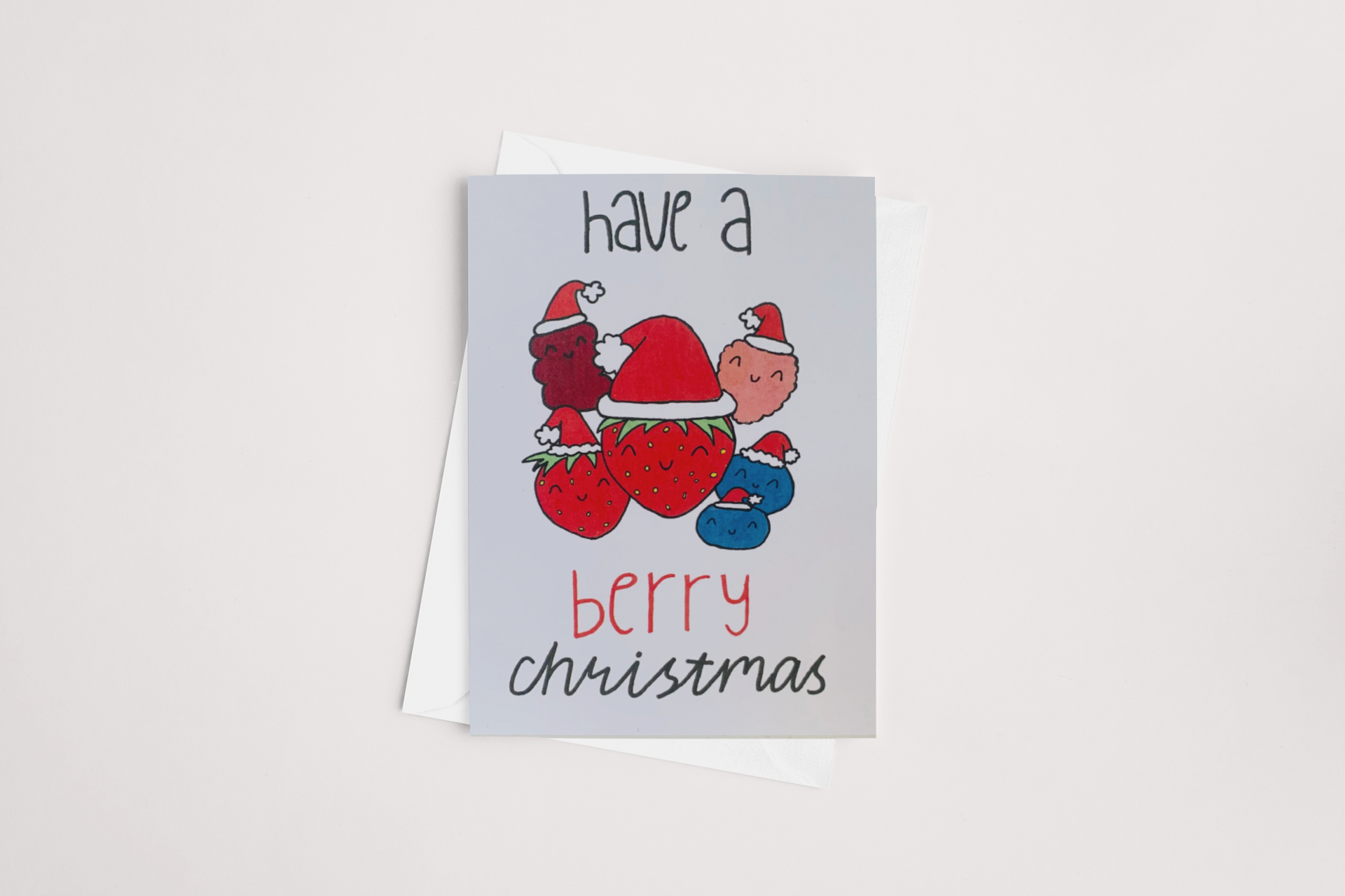 The Sweet Pea Creations "Berry Christmas Card" features an adorable illustration of strawberries, raspberries, and blueberries wearing Santa hats. It comes with the cheerful message "Have a berry Christmas" in a playful font. This delightful blank card includes a white envelope, making it perfect for spreading festive cheer.