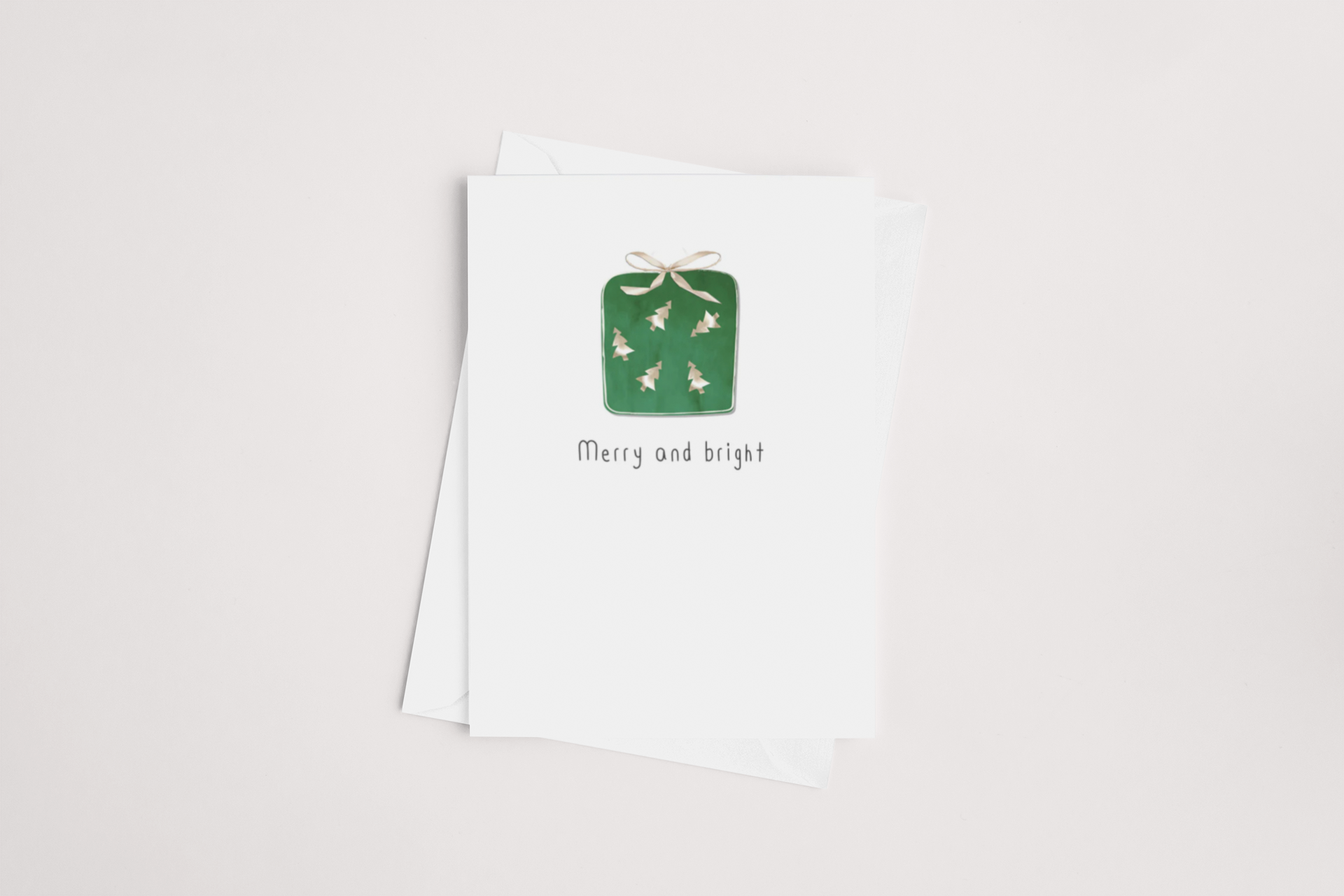 Introducing the Merry and Bright Christmas Card by iCandy - a minimalist holiday card showcasing a green gift box adorned with a beige ribbon and accented with small white stars. Beneath the box, the message "Merry and bright" is elegantly displayed. The blank interior card comes paired with a slightly larger white envelope, all set against a simple, plain white backdrop—ideal for purchasing in multiples.