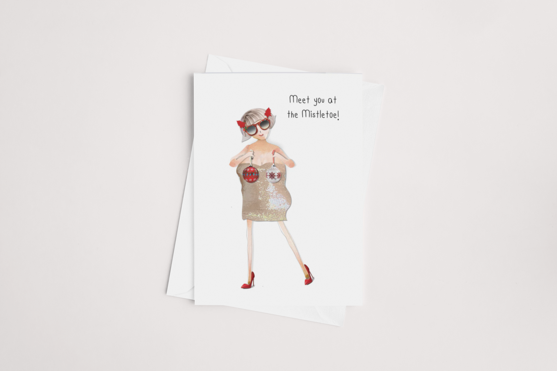 The iCandy "Meet at the Mistletoe" Christmas card features a festive cartoon woman wearing a sparkling dress, sunglasses, red heels, and Christmas ornament earrings. Her hair is styled with red ribbons. The cover text says "Meet you at the Mistletoe!" and the card comes blank inside with a white envelope.