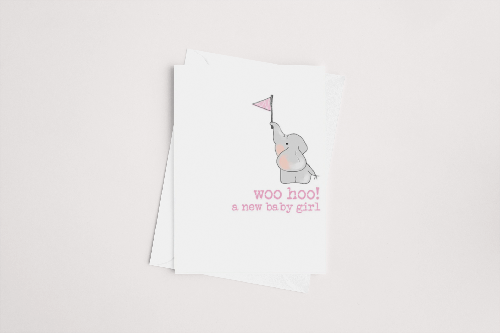 The Woohoo Baby Girl Card by Dandelion features an adorable illustration of a gray elephant holding a pink flag with its trunk, accompanied by the message "woo hoo! a new baby girl" in pink text. This charming card comes with a blank white envelope, making it perfect for celebrating the joyous occasion of welcoming a new baby girl.