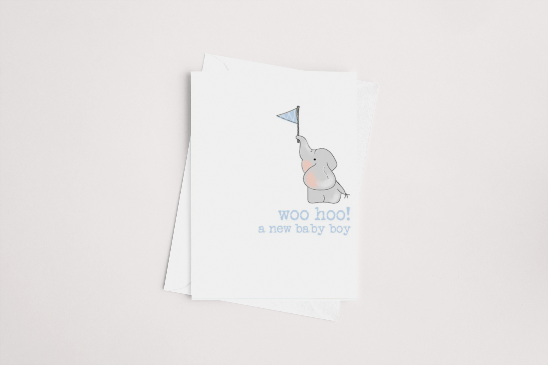 The Woohoo Baby Boy Card by Dandelion showcases a gray elephant holding a blue pennant on its white cover, with the words "woo hoo! a new baby boy" displayed below. The card is blank inside for your personalized message and comes with a white envelope, set against a light background.