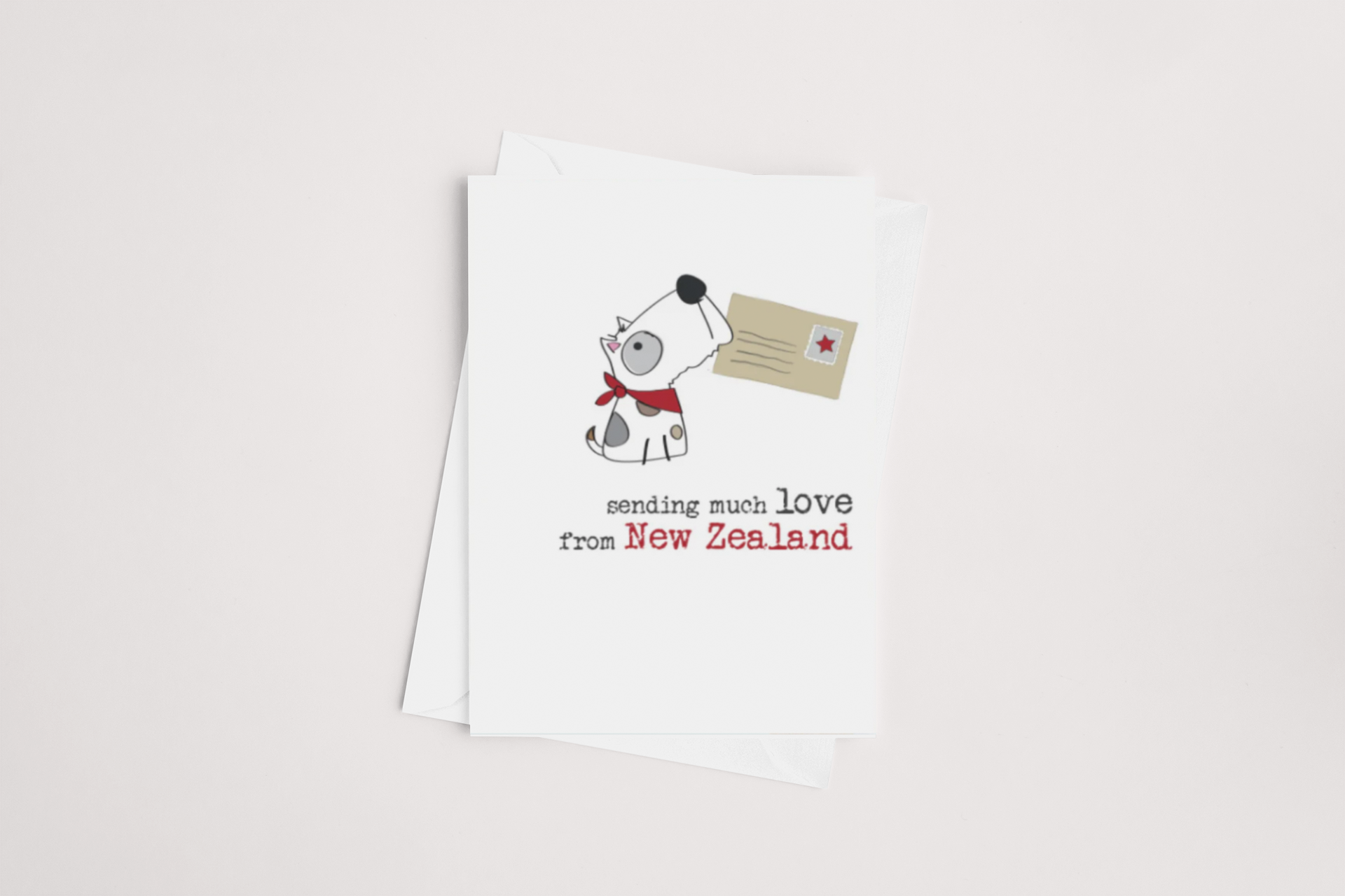 The "Love from NZ Card" by Dandelion features a cartoon dog with black spots and a red collar, holding an envelope in its mouth against a white background. The text on the card reads "sending much love from New Zealand," and it comes with a brown envelope ready for your special message.