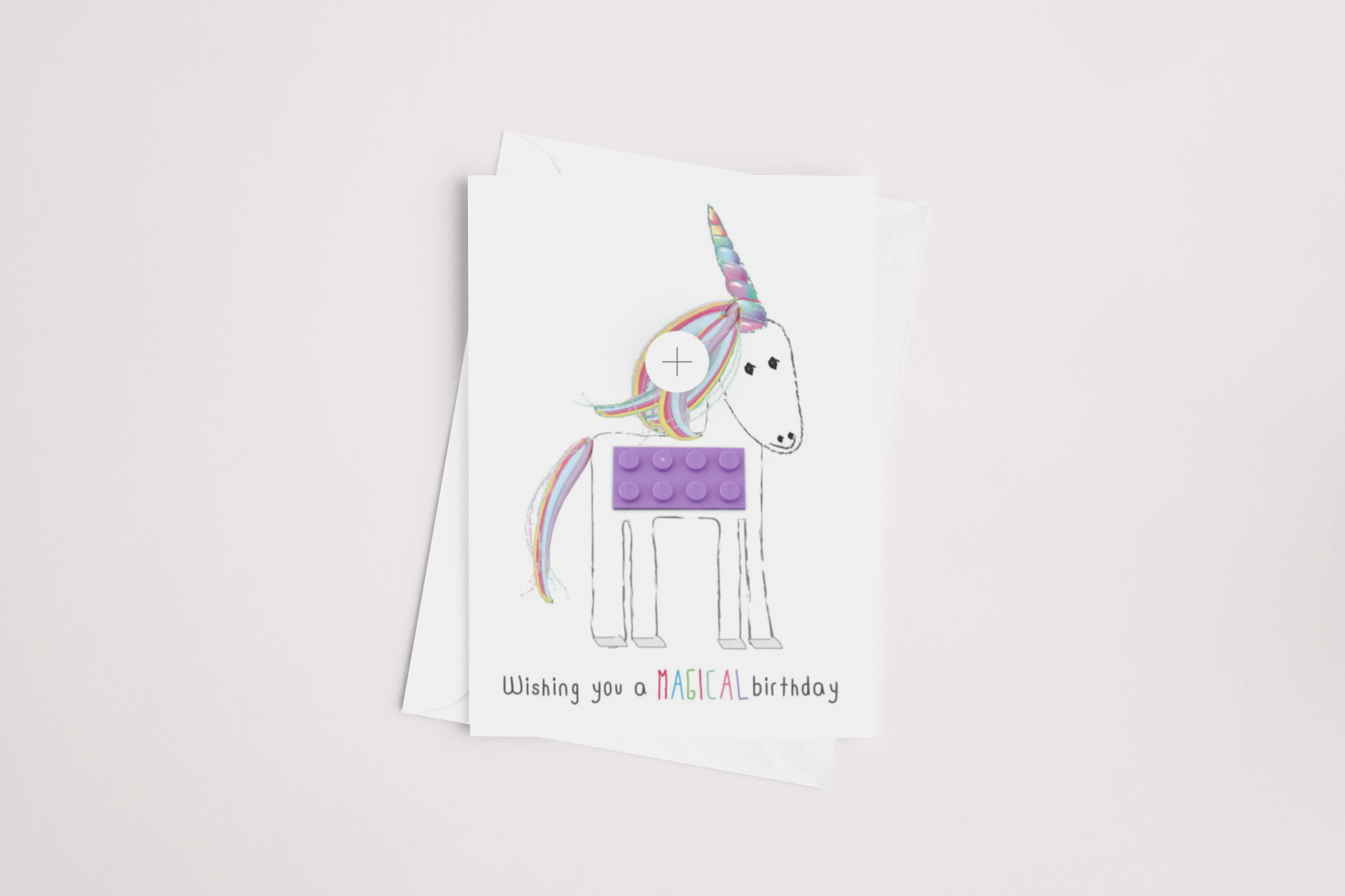 Celebrate with the iCandy Lego Unicorn Birthday Card, showcasing a unicorn adorned with a rainbow mane and a playful, LEGO-like purple brick body. The card's cheerful cartoon style is completed by the message "Wishing you a MAGICAL birthday" at the bottom. With its blank interior awaiting your personal touch, this card comes paired with an envelope set against a light background.